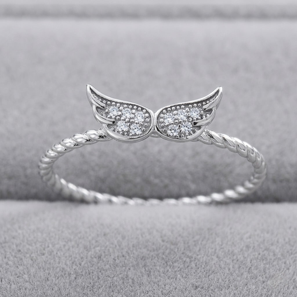 Sterling silver angel wings ring with white sapphires on grey display 
