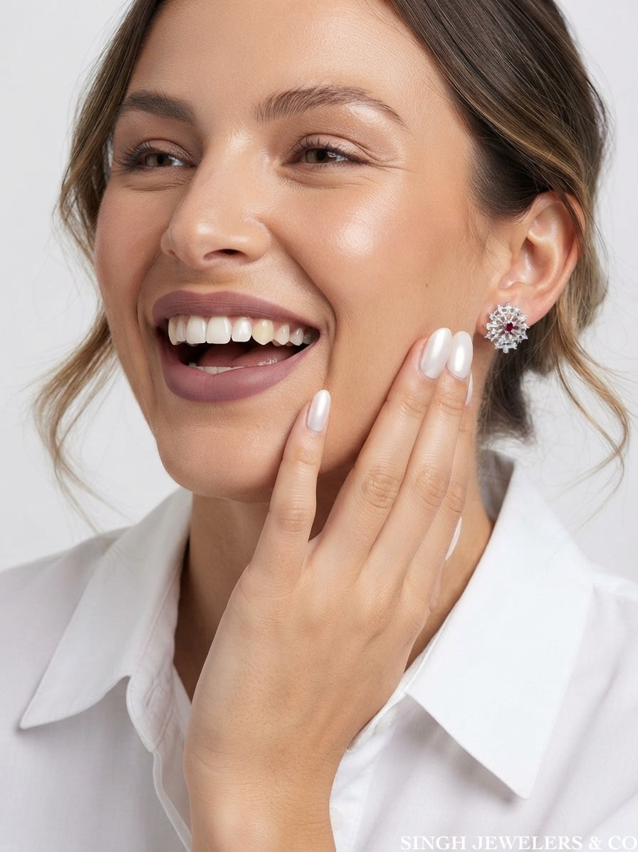 A close-up lifestyle shot of a smiling woman wearing a silver-toned crystal cluster earring, with her hand resting on her cheek against a clean white background.