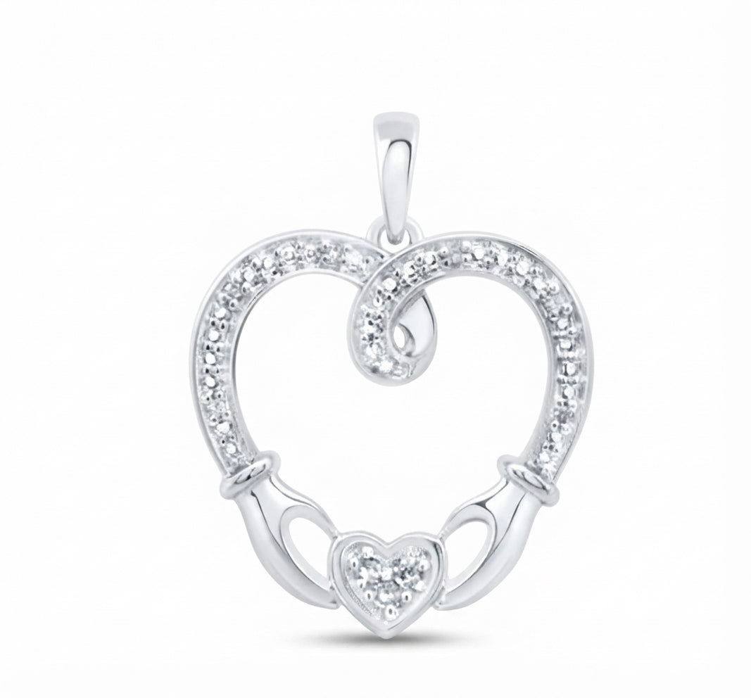 A sterling silver heart-shaped pendant with a Celtic claddagh design, featuring a heart in the center, two hands holding it, and a border of small clear stones, shown on a white background.