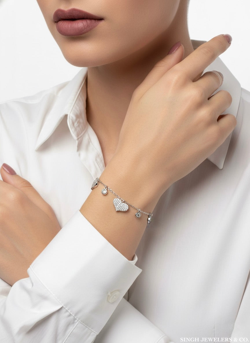 Person wearing a silver bracelet with heart charms on a white background
