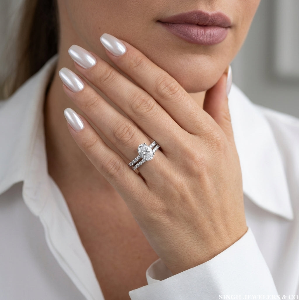 A close-up lifestyle shot of a woman wearing a silver engagement ring with a round center stone and a matching pave band, styled with a white collared shirt.
