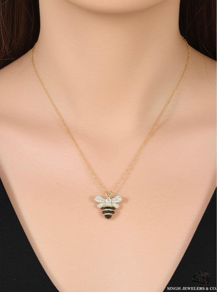 Woman wearing 10k gold honey bee charm necklace with black and white diamonds